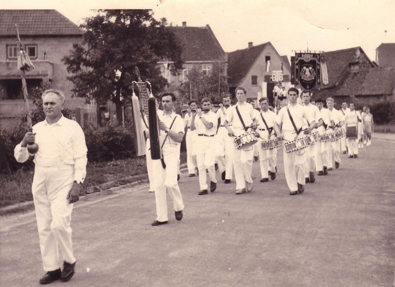 Der Spielmannszug des TSV Braunshardt beim Umzug durch Braunshardt 1955: vorneweg der Tambourmajor mit Stab, dahinter Schellenbaum, Querpfeifen und Trommeln, alle in weißer Uniform